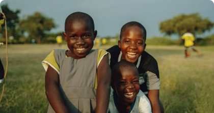 three children with big smiles in an open field